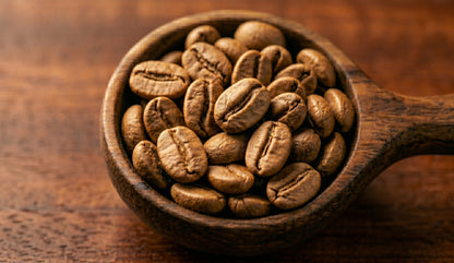 Close‑up of roasted coffee beans in a wooden scoop on a warm wooden surface. Rich texture and earthy tones highlighting the natural beauty and craftsmanship behind Kenya Kafe Cup’s coffee origins.